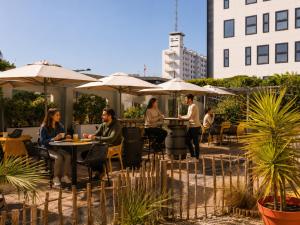 a group of people sitting at tables with umbrellas at ibis Bordeaux Centre Meriadeck in Bordeaux