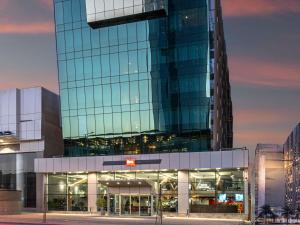 a large glass building in front of a city at Ibis Riyadh Hotel Al Muhammadiyah United Company Branch in Riyadh