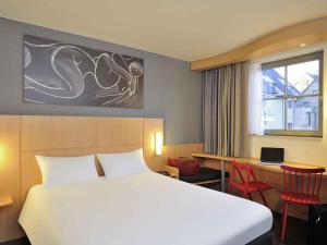 a bedroom with a bed and a desk with a laptop at ibis De Panne in De Panne +69 photos