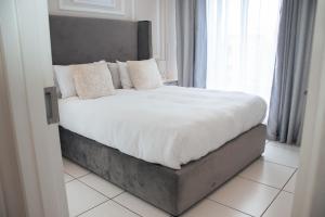 a bedroom with a large bed with white sheets and pillows at Luxury Sunset Gem with Power Backup in Sandton +15 photos