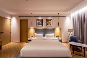 a bedroom with a large white bed and a desk at Radisson Hotel Nathdwara in Nāthdwāra