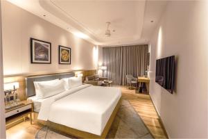 a hotel room with a white bed and a desk at Radisson Hotel Nathdwara in Nāthdwāra