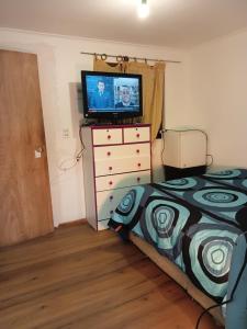 a bedroom with a bed and a television on a dresser at Cabañas Laguna Verde Valparaiso in Laguna Verde