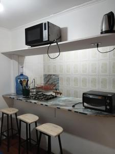 a kitchen with a counter with stools and a microwave at Cabañas Laguna Verde Valparaiso in Laguna Verde