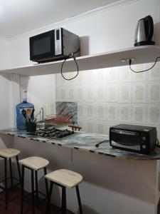 a kitchen with a counter with a microwave and stools at Cabañas Laguna Verde Valparaiso in Laguna Verde