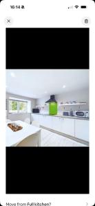 a kitchen with white cabinets and a large tv at The Old Workshop in Innerwick