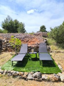 three chairs and a table on a patch of grass at Paradise kosirina in Murter
