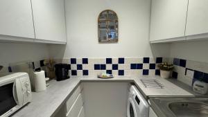 a kitchen with white cabinets and blue and white tiles at Studio Mirepoix in Mirepoix