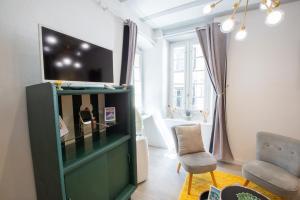 a living room with a flat screen tv on top of a cabinet at Suite Lyséa - Balnéothérapie au Coeur d'Annecy in Annecy