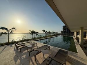 a swimming pool with chairs and a view of the ocean at Edificio Reserva del Mar Bello Horizonte in Playa Bello Horizonte