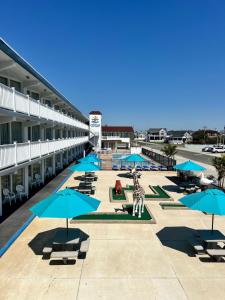 a resort with blue umbrellas and chairs and a building at Compass Family Resort in Wildwood Crest
