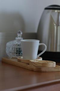 a coffee cup sitting on a wooden tray with a glass container at Hotel do Feijão in Cachoeira Paulista