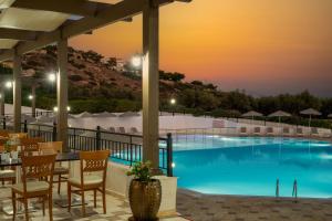 a hotel patio with a pool at dusk at Mare Village in Ierapetra