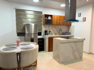 a kitchen with a table and a stainless steel refrigerator at Suite Rosedelco in Puerto Villamil
