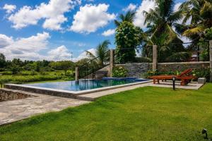 a pool in a yard with a bench and grass at Emerald Edge Villa in Minuwangoda