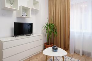 a white living room with a tv and a table at Joy Apartament in Nehoiu