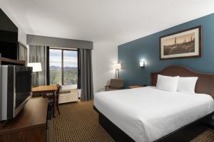 a hotel room with a bed and a flat screen tv at Tombstone Grand Hotel, a Baymont by Wyndham in Tombstone +19 photos