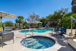 a pool with a hot tub with chairs and an umbrella at Tombstone Grand Hotel, a Baymont by Wyndham in Tombstone