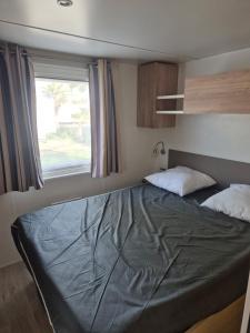 a large bed in a room with a window at Mobilhome, Camping Le Marisol in Torreilles
