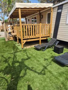 a yard with a deck with chairs and a house at Mobilhome, Camping Le Marisol in Torreilles