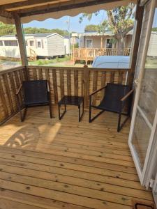 a deck with two chairs and a bed on it at Mobilhome, Camping Le Marisol in Torreilles +2 photos