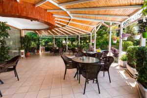 an outdoor patio with tables and chairs under a wooden ceiling at JB Hotel in Sarandë