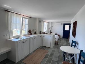 a kitchen with white cabinets and a table and a sink at Kimoliatiko in Kimolos