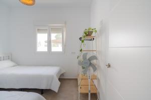a white bedroom with a bed and a ladder with a fan at La Tertulia in Zahora
