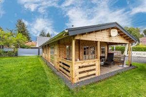 a wooden cabin with a black roof on a yard at Adler Sommerhaus Oderwitz in  Oderwitz