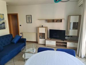 a living room with a blue couch and a tv at Alloro in Ankaran