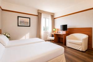 ein Hotelzimmer mit zwei Betten und einem Stuhl in der Unterkunft SHG Hotel Bologna in Zola Predosa + 55 Fotos