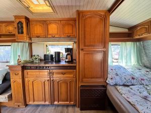 a kitchen with wooden cabinets and a bed in an rv at Kleine Auszeit in Schermbeck +12 photos