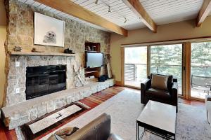 a living room with a stone fireplace and a television at Timberline Condominiums 2 Bedroom Deluxe Unit D2D in Snowmass Village