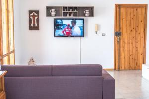 a living room with a couch and a tv on the wall at Villa Tommi a due passi dal mare in Fontane Bianche