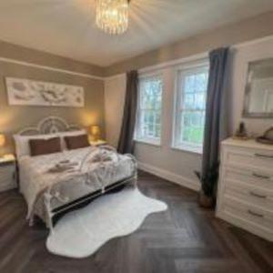 a bedroom with a bed and a dresser and windows at Hilston Gate House in Skenfrith