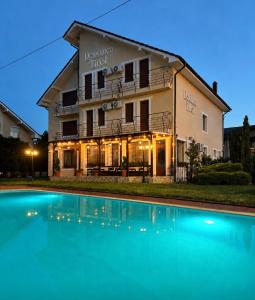 a hotel with a swimming pool in front of a building at Pensiunea Tirol Baile Felix in Baile Felix