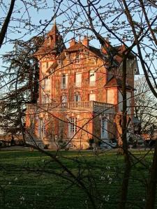 a large brick building in a field with trees at Villa du Sauzin in Cronat
