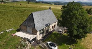 an old house with a car parked in front of it at La ferme de Jouane in Besse-et-Saint-Anastaise