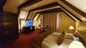 a hotel room with a bed and a flat screen tv at GARDEN Club - Hotel & Restaurant - FREE Outdoor Pool & Parking in Braşov