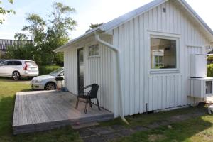 a small white building with a chair on a deck at Strandskatan 102 in Halmstad