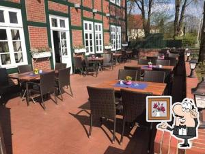 a patio with tables and chairs and a building at Altes Posthaus Ahlhorn in Großenkneten +4 photos