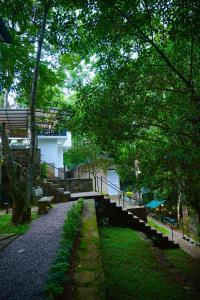 a path with benches and a building in a park at Villa Whispering Leaves Kandy in Galaha Town