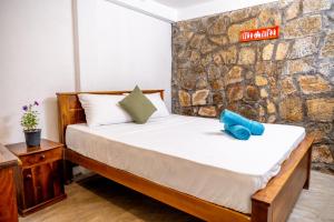 a bed in a room with a stone wall at Villa Whispering Leaves Kandy in Galaha Town