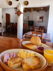 a plate of food on a wooden table with breakfast foods at Posada Yacoraite Tilcara in Tilcara