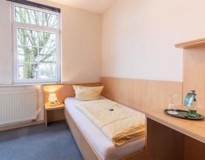 a small bedroom with a bed and a window at Altes Posthaus Ahlhorn in Großenkneten