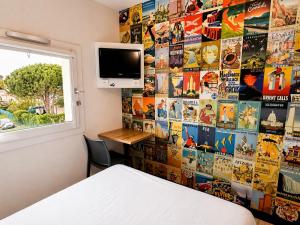 a bedroom with a wall covered in movie posters at hotelF1 Orange Centre Echangeur A7 A9 in Orange