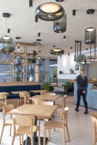 a person walking in a restaurant with tables and chairs at Dasbreitehotel am Rhein in Basel
