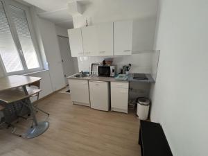 a small kitchen with white cabinets and a table at Le Saint Vaast - Studio au centre d'Arras in Arras