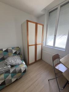 a bedroom with a bed and a chair and two windows at Le Saint Vaast - Studio au centre d'Arras in Arras