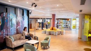 a woman sitting on a couch in the lobby of a store at Mercure Paris Massy Gare TGV in Massy